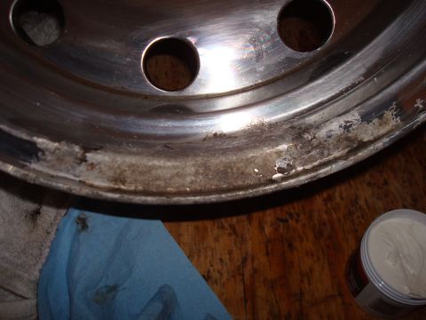 1992 Ford Bronco - The aluminum wheel rim shows significant corrosion and pitting along its edge, with a polishing compound and cloth present.