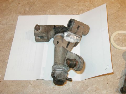 1993 Ford Bronco - Metal shifter linkage part with visible weld repairs, placed on a piece of paper.