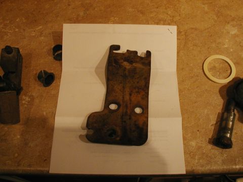 1993 Ford Bronco - A rusted metal bracket and associated hardware are laid out on a piece of paper.