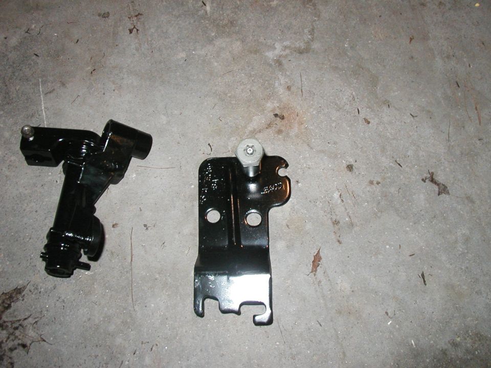 Two black metal shifter components on a concrete surface