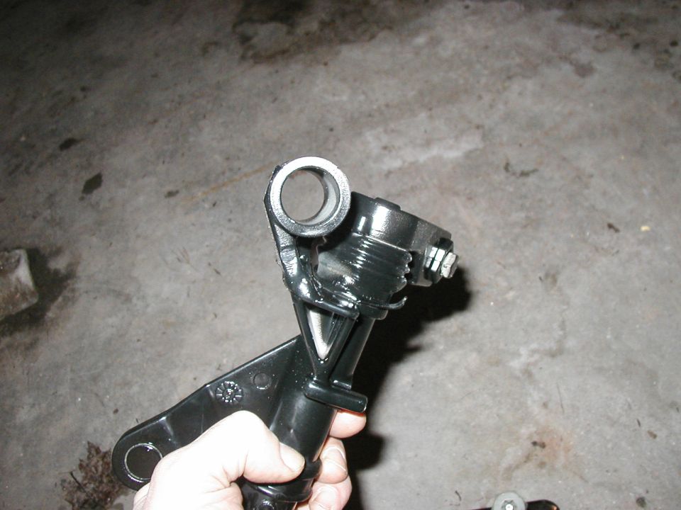 Black metal shifter linkage part held in hand, with a circular opening at the top