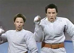 1989 Ford Bronco - Two men in grey sweatshirts are shown from the chest up, one holding a white object.