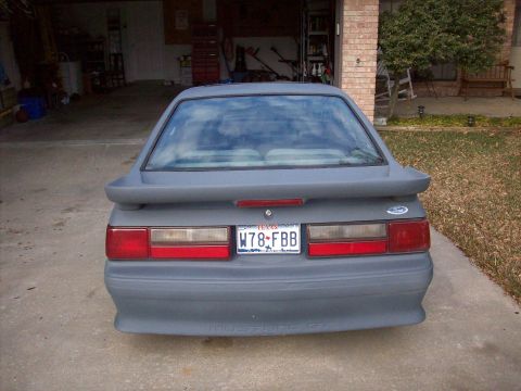 1989 Ford Mustang - Rear view of a 1989 Ford Mustang GT in primer gray, parked in a driveway.