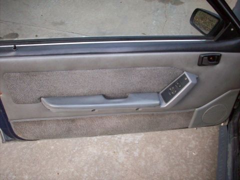 1989 Ford Mustang - Interior door panel of a 1989 Ford Mustang, showing the power window controls and speaker grille.