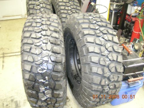 1996 Ford Bronco - Several large, aggressive off-road tires are stacked in a garage setting, with a date stamp visible.