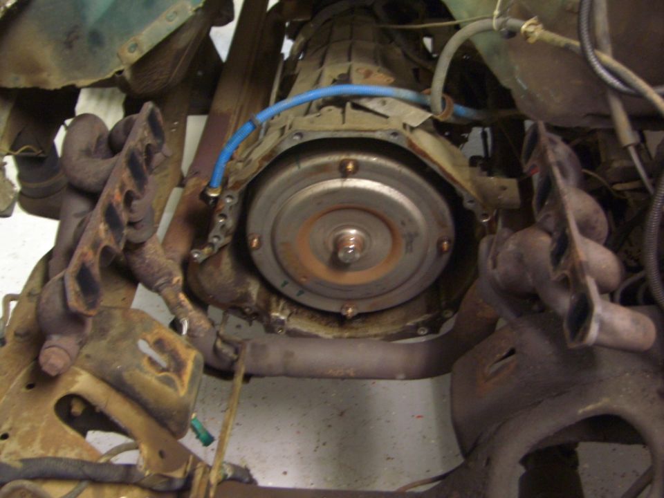 Transmission bellhousing with torque converter and rusty exhaust manifolds viewed from below