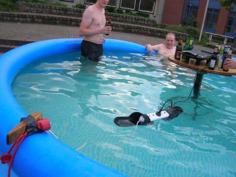 1993 Ford Probe - Two men relax in an inflatable pool, with a floating power strip and a table laden with drinks.