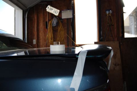 1985 Mercury Grand Marquis - A car spoiler is taped and ready for installation in a garage setting.