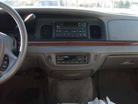 1993 Ford Crown Victoria - Interior view across the dashboard of a Ford Crown Victoria with tan/grey trim and a woodgrain accent strip, showing the factory cassette/C…