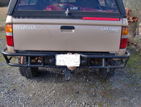 1978 Ford Bronco - Rear view of a tan Toyota Tacoma pickup truck with a custom bumper and a softopper installed.