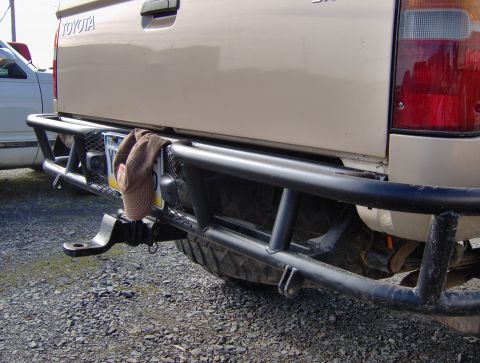 1978 Ford Bronco - Aftermarket rear bumper and tow hitch assembly on a Toyota truck, with a spare tire visible underneath.