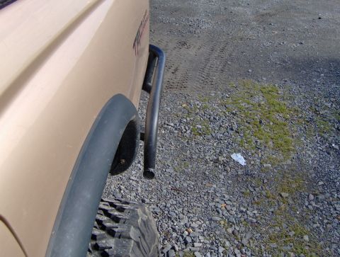 1978 Ford Bronco - A close-up of a tan pickup truck's rear fender and tire, with a black fender flare and a portion of a roll bar visible.