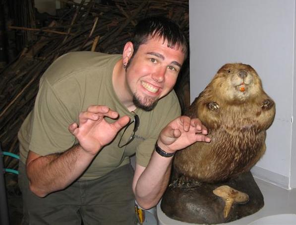Man making claw hands next to a taxidermied beaver with orange teeth
