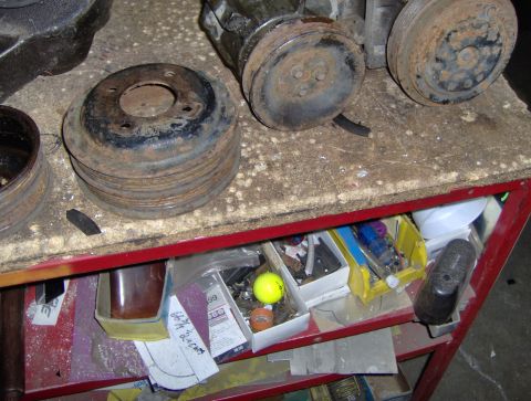 1978 Ford Bronco - Various engine pulleys and parts are shown on a workbench, with a shelf below containing tools and other items.