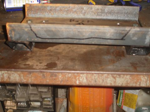 1989 Ford Bronco - A metal winch mount with cut lines is shown on a workbench.