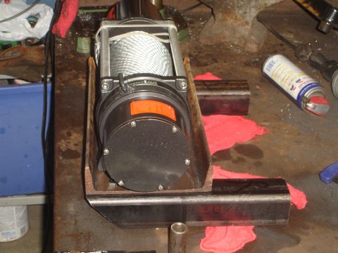 1989 Ford Bronco - Winch and custom metal bracket on a workbench, possibly for a vehicle modification.