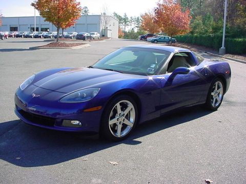 2005 Chevrolet Corvette - A blue 2005 Chevrolet Corvette is parked in a lot with trees and a building in the background.