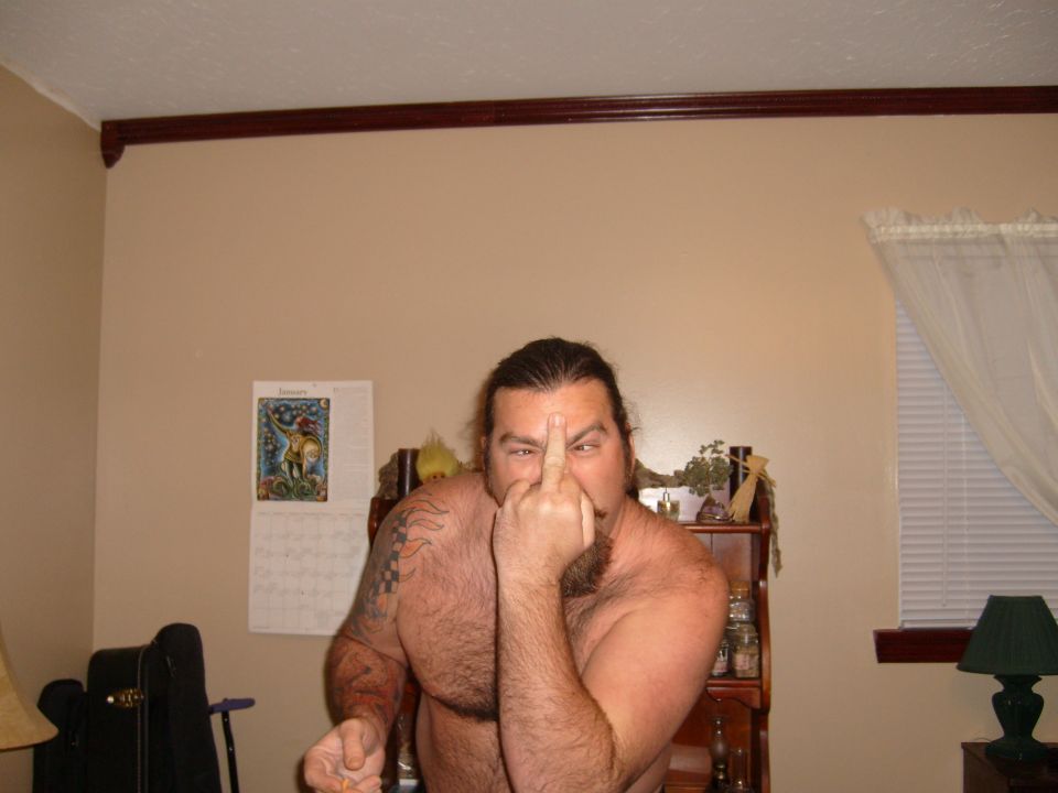 Man with long hair and beard gives middle finger to camera