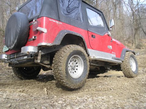 2002 Ford Sport Trac - This red Jeep Wrangler navigates a muddy off-road trail, its capabilities.