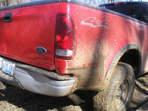 2002 Ford Sport Trac - Mud-splattered red Ford pickup truck with a "4x4" decal, seen off-road.