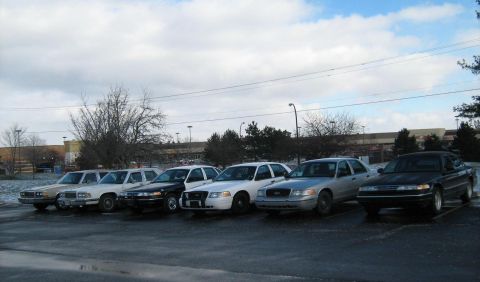 1988 Mercury Grand Marquis - Several police interceptor sedans are parked in a lot on a cloudy day.