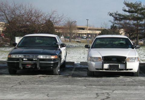 1988 Mercury Grand Marquis - Two Ford Crown Victoria police cars are parked side-by-side in a parking lot on a winter day.