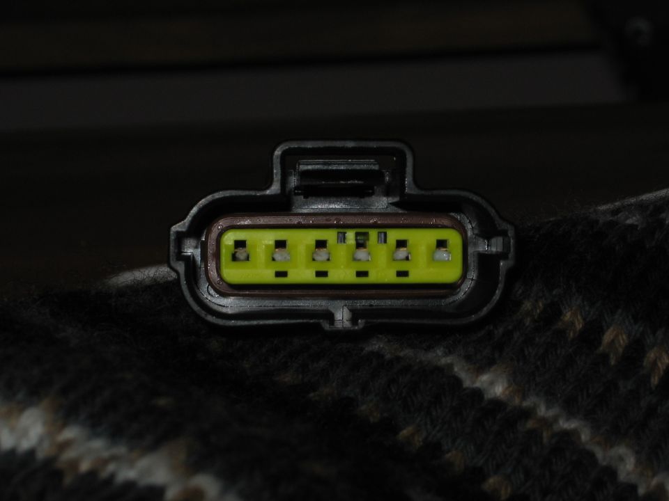 Close-up of a black electrical connector with a yellow insert holding six pins