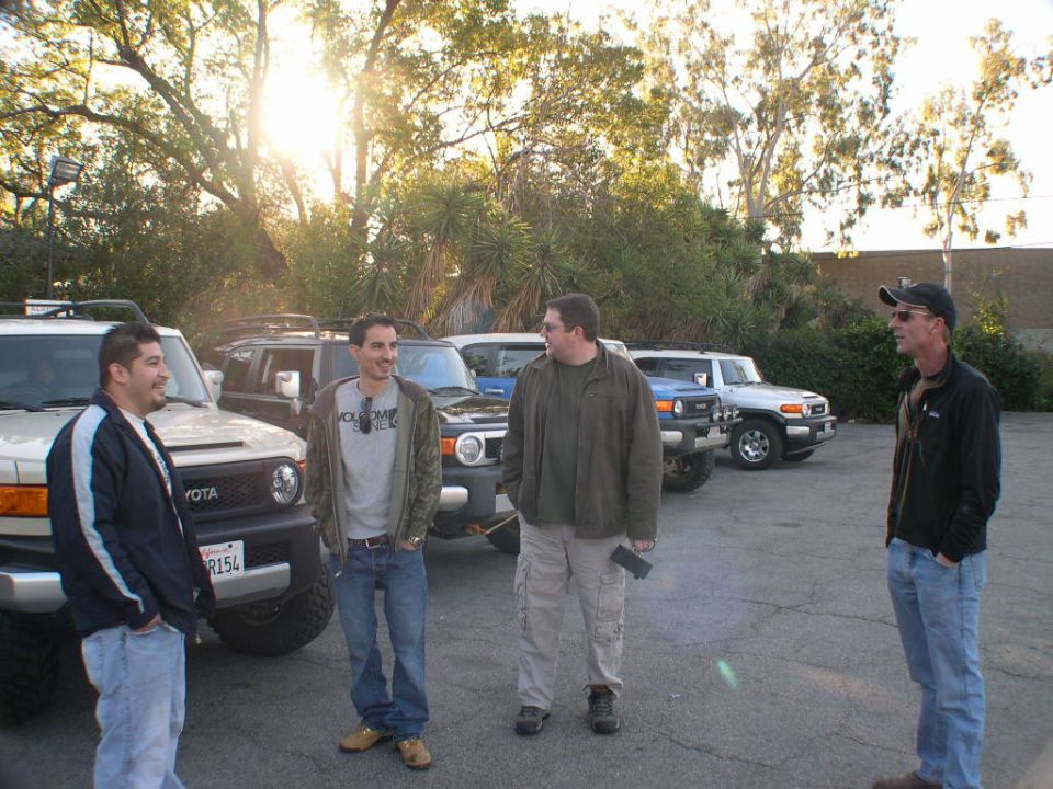 Four Toyota FJ Cruisers parked in a lot with four men standing nearby