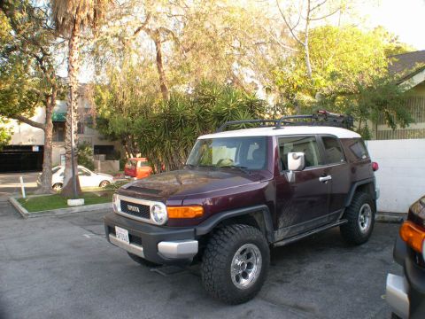 2007 Toyota FJ Cruiser - A dark purple 2007 Toyota FJ Cruiser is parked in a lot with trees and buildings in the background.