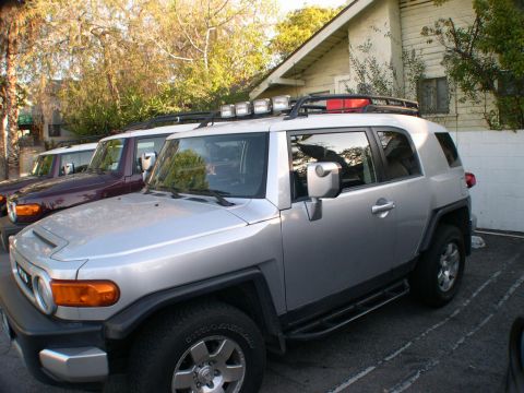 2007 Toyota FJ Cruiser - A silver 2007 Toyota FJ Cruiser is parked in front of a building, with two other FJ Cruisers visible behind it.