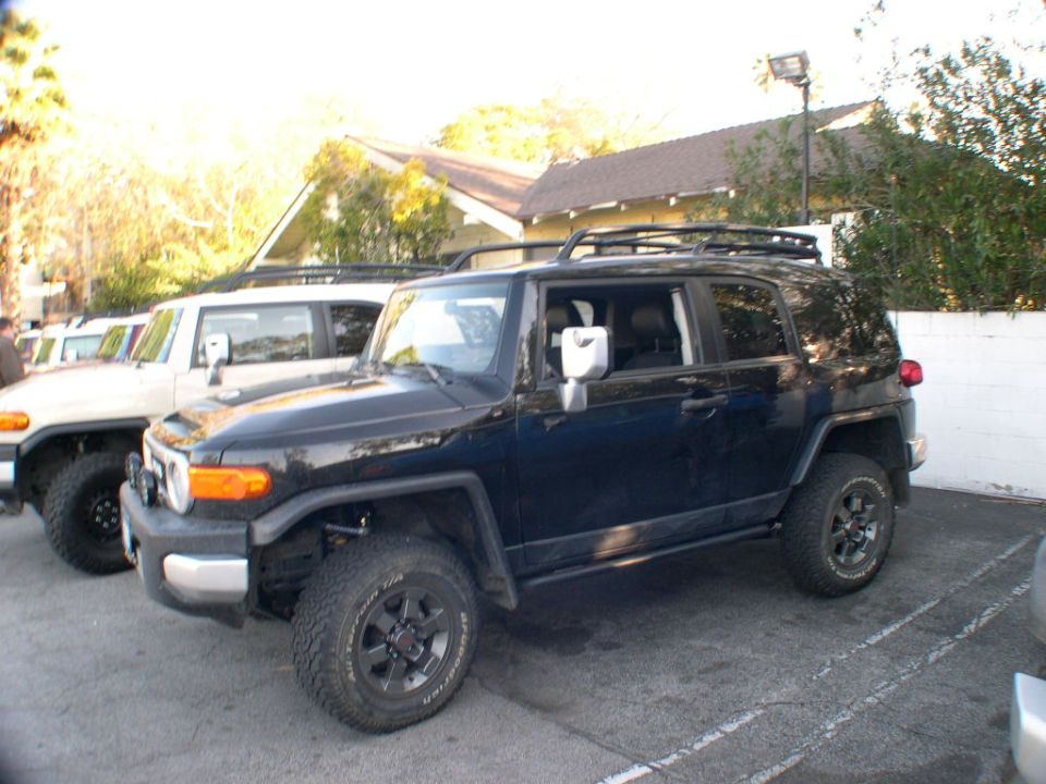 Black 2007 Toyota FJ Cruiser parked next to a white FJ Cruiser, viewed from the front three-quarter angle