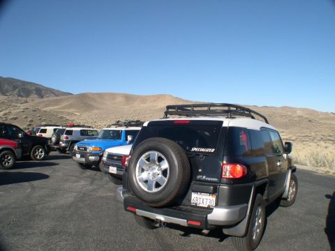 2007 Toyota FJ Cruiser - A group of FJ Cruisers are parked in a lot with a mountainous backdrop under a clear blue sky.