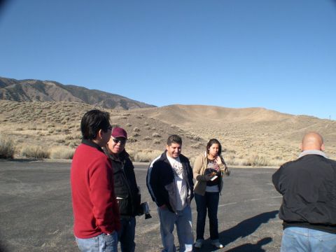 2007 Toyota FJ Cruiser - A group of people stand in a paved area with arid hills under a clear blue sky.