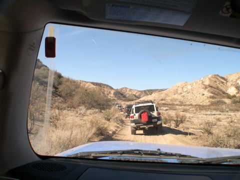 2007 Toyota FJ Cruiser - A convoy of Toyota FJ Cruisers navigates a dusty trail through a desert canyon.
