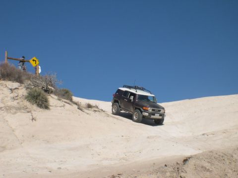 2007 Toyota FJ Cruiser - A 2007 Toyota FJ Cruiser navigates a sandy incline under a clear blue sky.
