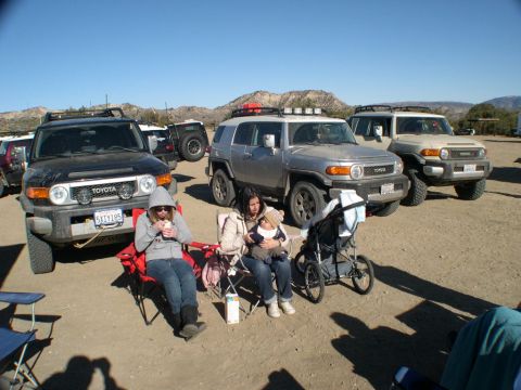 2007 Toyota FJ Cruiser - Several Toyota FJ Cruisers are parked in a dusty, outdoor location, with people relaxing in chairs nearby.