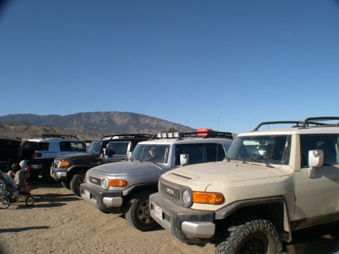 2007 Toyota FJ Cruiser - Several Toyota FJ Cruisers are parked in a line under a clear blue sky with mountains in the background.