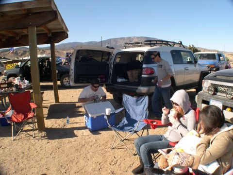 2007 Toyota FJ Cruiser - People relax and eat near several vehicles at an outdoor event.