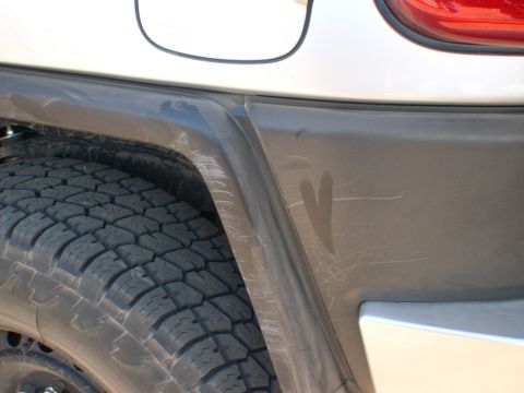 2007 Toyota FJ Cruiser - Close-up of the rear fender and tire of a 2007 Toyota FJ Cruiser, showing scratches on the trim.