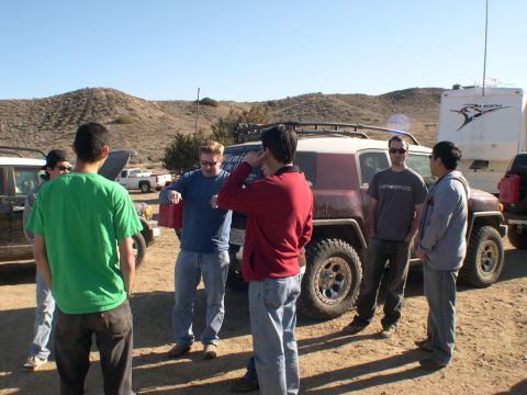 2007 Toyota FJ Cruiser - A group of people gather around a maroon Toyota FJ Cruiser in a desert landscape.