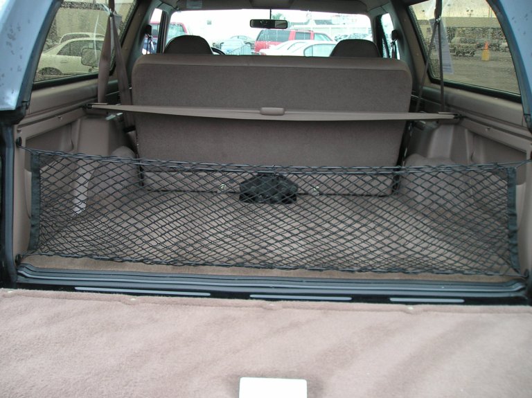 Back cargo area of an SUV with a cargo net stretched across it, showing the rear seats and a storage cover