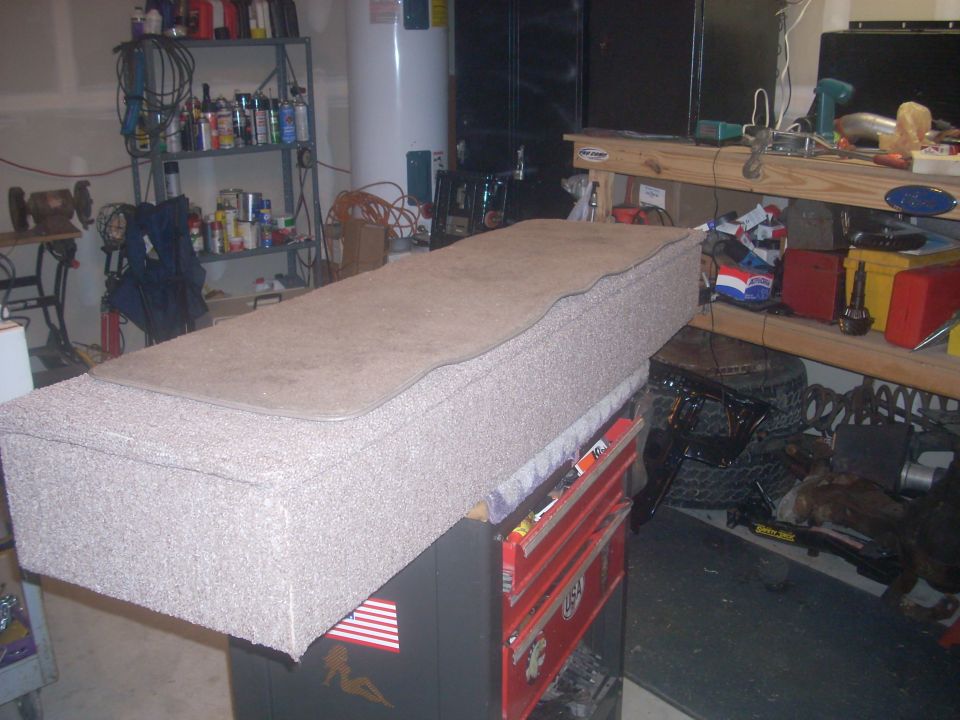 Carpeted storage box on top of a red toolbox in a garage