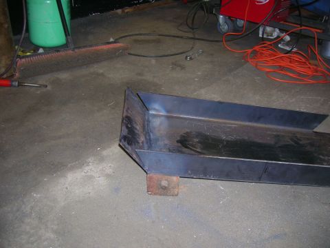 1979 Ford Bronco - A custom metal channel part sits on the floor of a garage, with tools and equipment in the background.