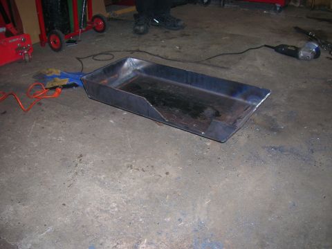 1979 Ford Bronco - A custom-fabricated metal pan with a section removed from one corner sits on a concrete floor.