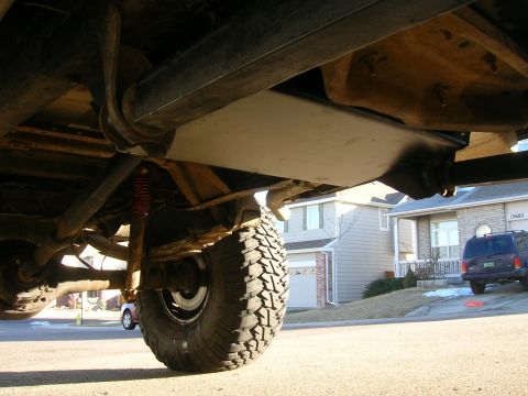 1979 Ford Bronco - The undercarriage of a 1978 Ford Bronco is visible, with a focus on the rear suspension components and a large tire.