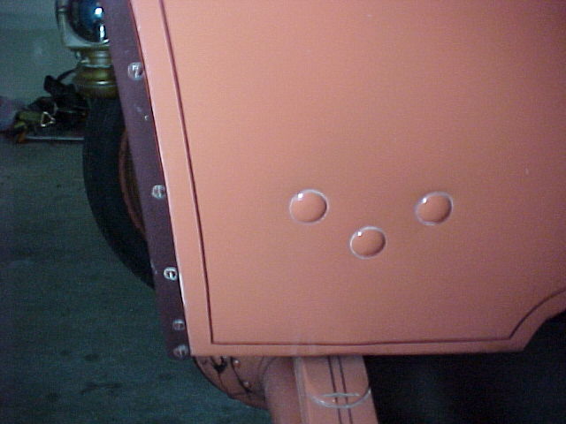 Salmon-colored body panel with three raised circular blisters