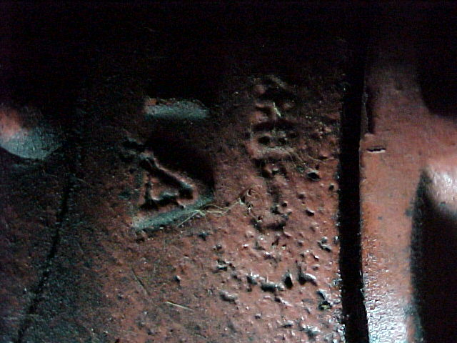 Close-up of cast markings and a triangle symbol on a dirty metal part