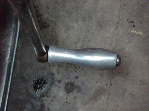 1912 Ford Model T - A silver exhaust pipe lies on a concrete surface, possibly awaiting installation or repair.