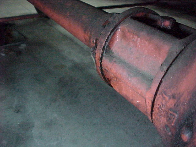 Rusty cylindrical exhaust muffler or canister under a vehicle