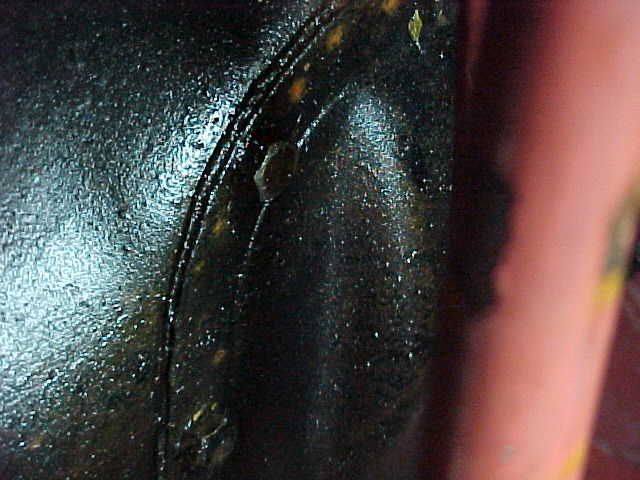 Dark close-up of an oily curved metal surface